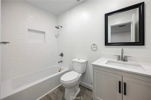 a bathroom with a toilet sink vanity tub and mirror