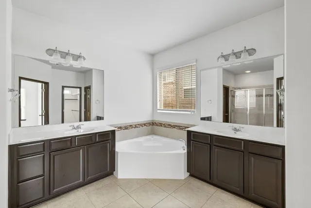 a bathroom with a granite countertop double vanity sink a mirror and a bathtub