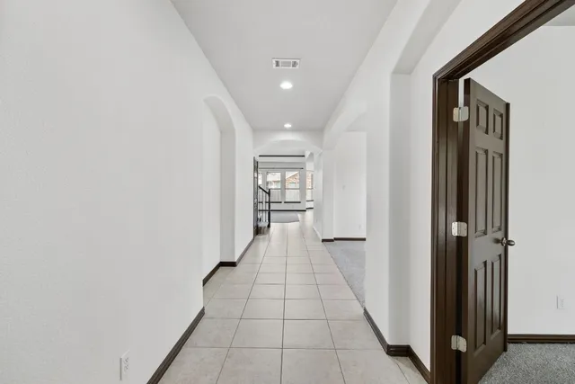 a view of a hallway with wooden floor and a bathroom