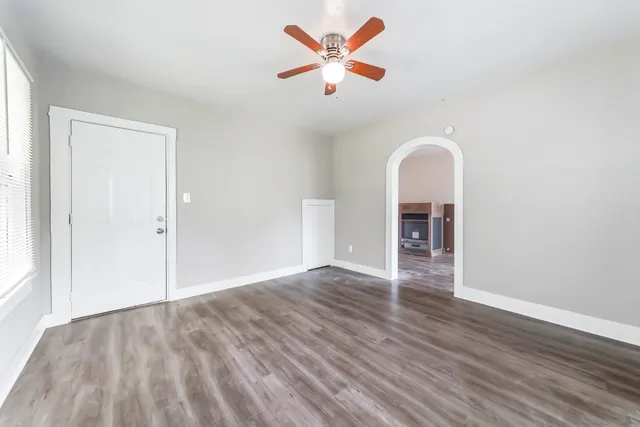 an empty room with wooden floor and a ceiling fan