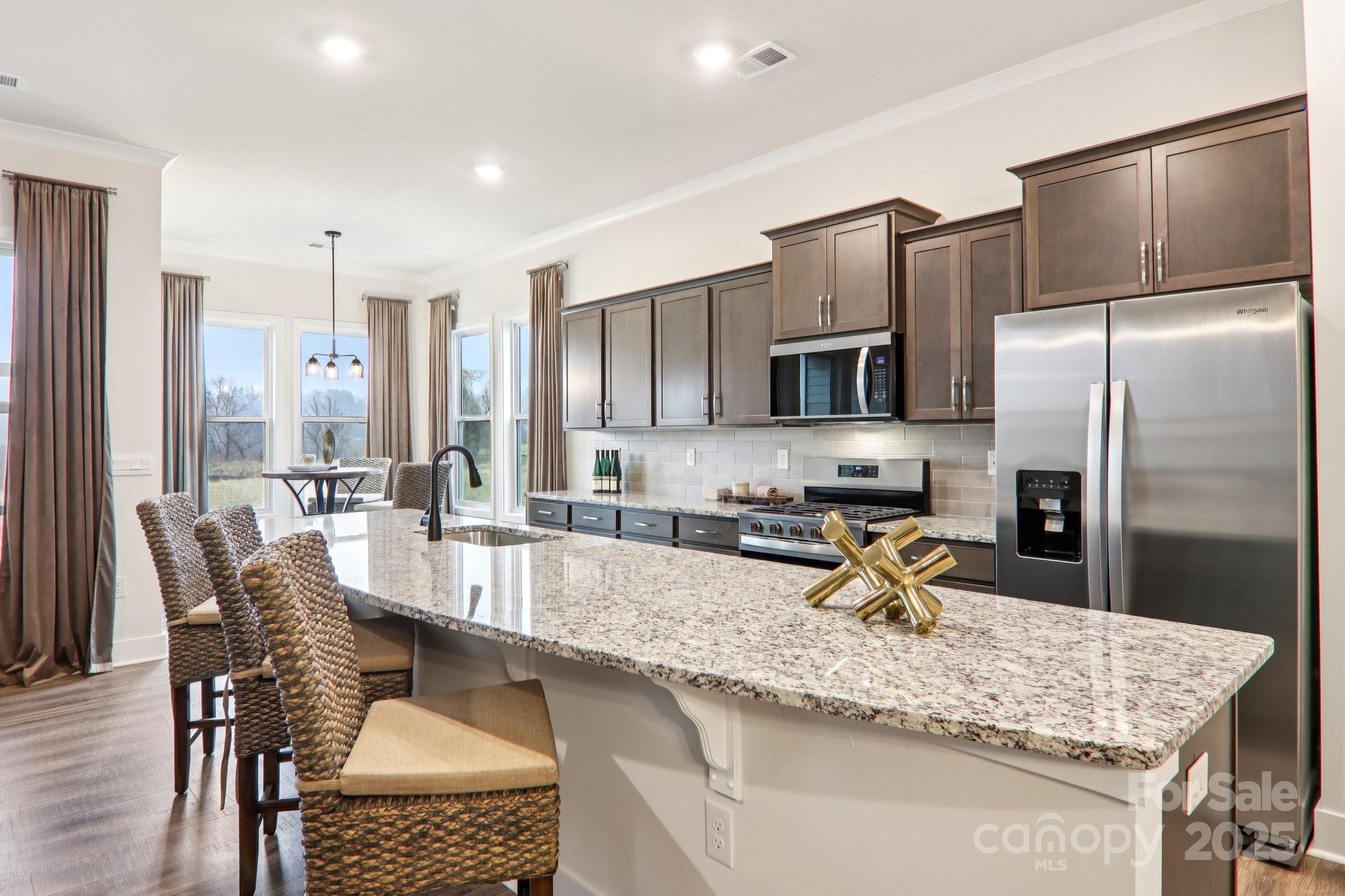 623 River Btm Road Fletcher, NC 28732 - Photo 10 of 48 a kitchen with stainless steel appliances granite countertop a stove a refrigerator a sink dishwasher a dining table and chairs with wooden floor