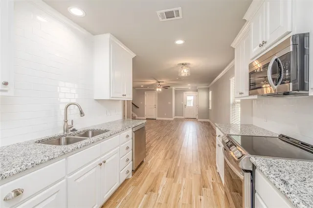 a large kitchen with stainless steel appliances granite countertop a sink dishwasher and cabinets with wooden floor