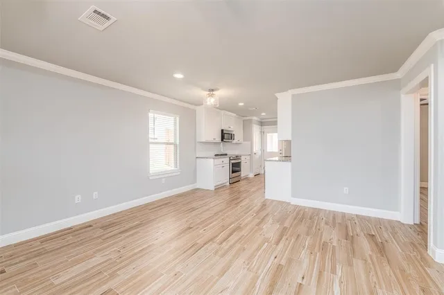 a view of empty room with wooden floor and window