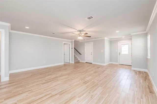 a view of an empty room with wooden floor and a ceiling fan