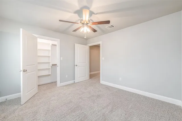an empty room with closet and a ceiling fan