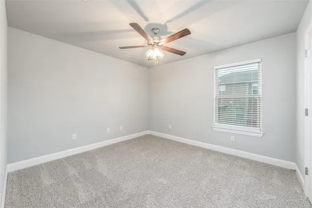 an empty room with a window and a fan