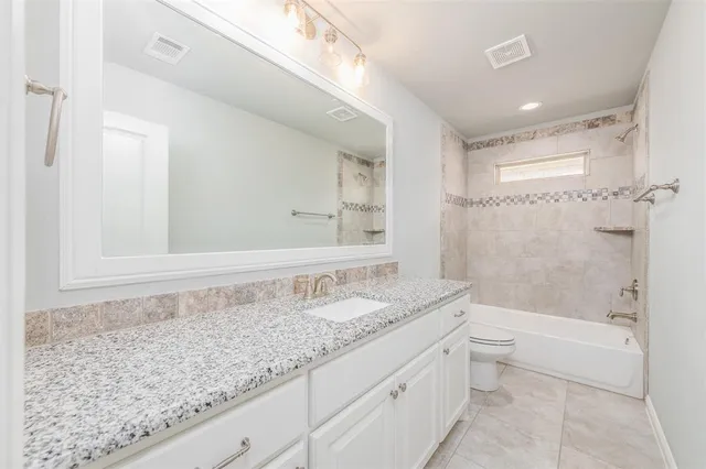 a bathroom with a granite countertop sink a toilet and bathtub