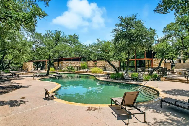 a view of a swimming pool and lounge chairs in back yard of the house