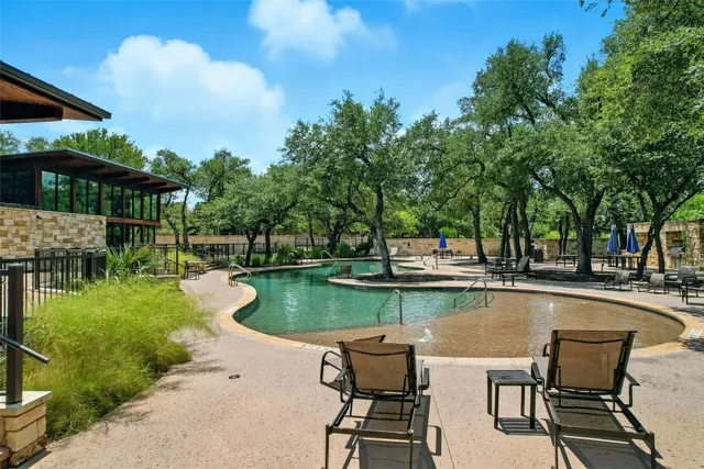 a view of a swimming pool with lawn chairs under an umbrella