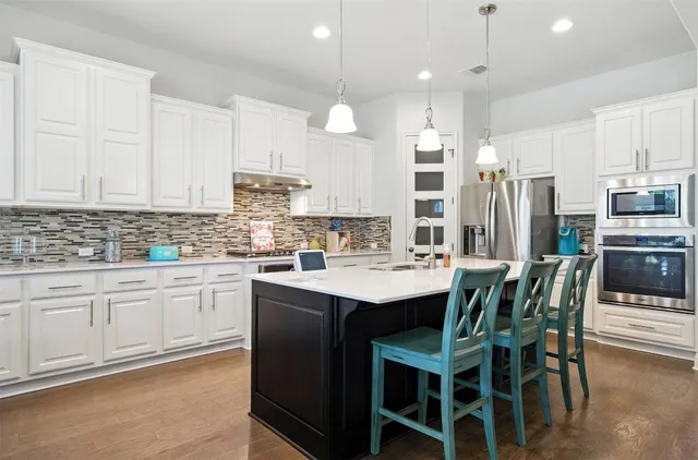a kitchen with stainless steel appliances kitchen island granite countertop a table chairs sink and cabinets