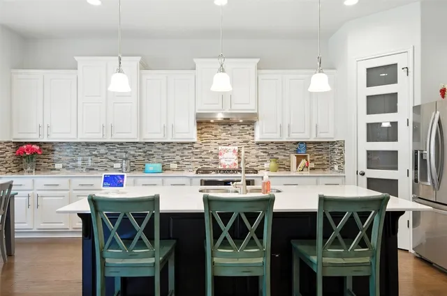 a kitchen with stainless steel appliances a white table and chairs in it