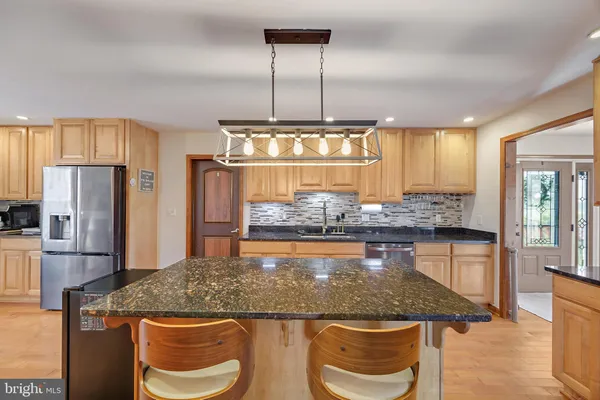 a kitchen with kitchen island granite countertop wooden cabinets and a refrigerator