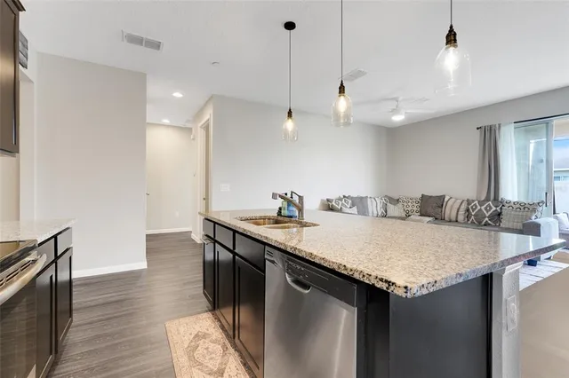 a kitchen with granite countertop a sink a counter space appliances and cabinets
