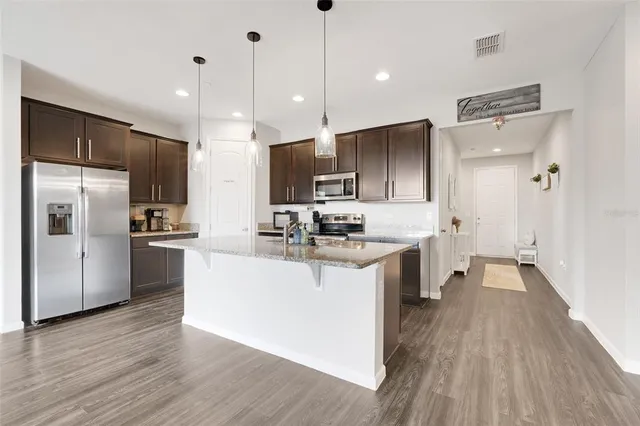 a kitchen with kitchen island a sink stainless steel appliances and cabinets