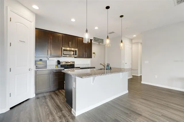 a kitchen with kitchen island a sink stainless steel appliances and wooden floor