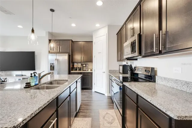 a kitchen with stainless steel appliances granite countertop a sink a stove and a refrigerator
