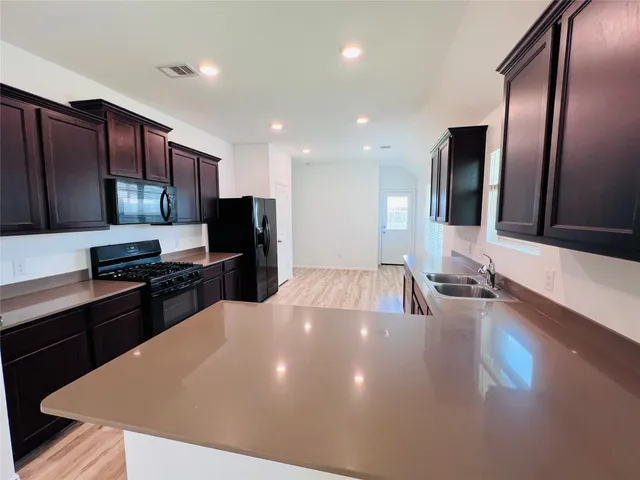 a large kitchen with stainless steel appliances a large counter top a stove a chimney a sink and a refrigerator