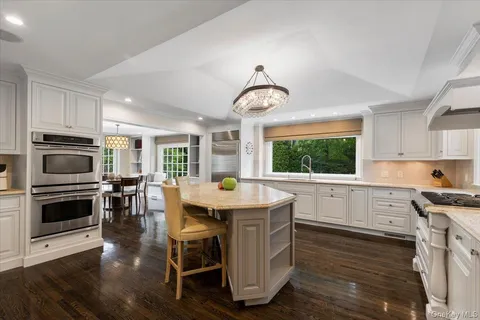 a kitchen with stainless steel appliances granite countertop a stove top oven a sink dishwasher a dining table and chairs with wooden floor