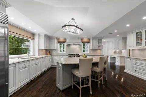 a kitchen with stainless steel appliances kitchen island granite countertop a table chairs and white cabinets