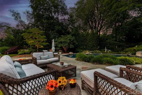 a view of a patio with couches table and chairs with plants and trees