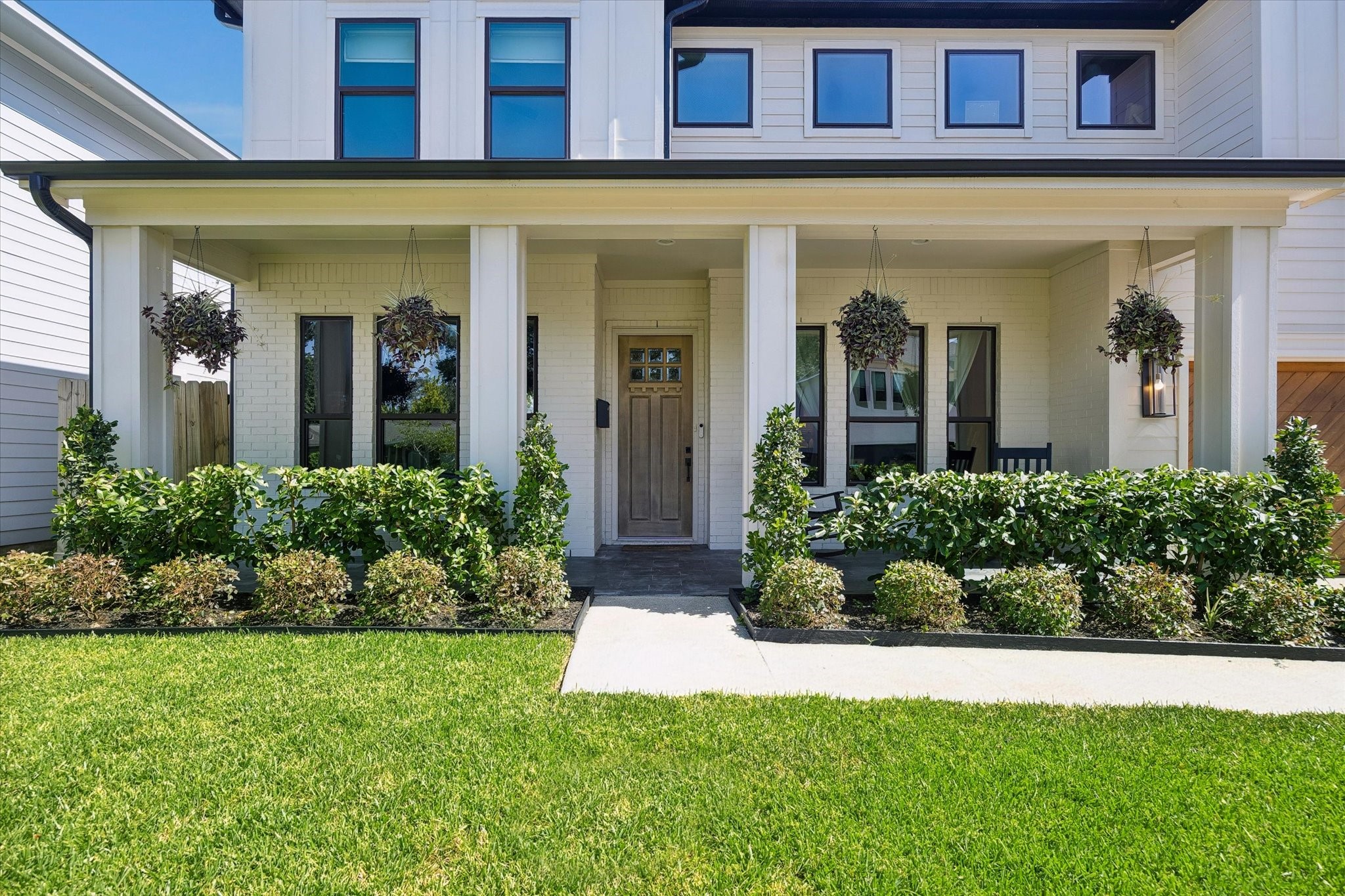 Welcome guests from the expansive covered front porch, complete with classic columns, manicured landscaping, and multiple seating areas that create a warm first impression.