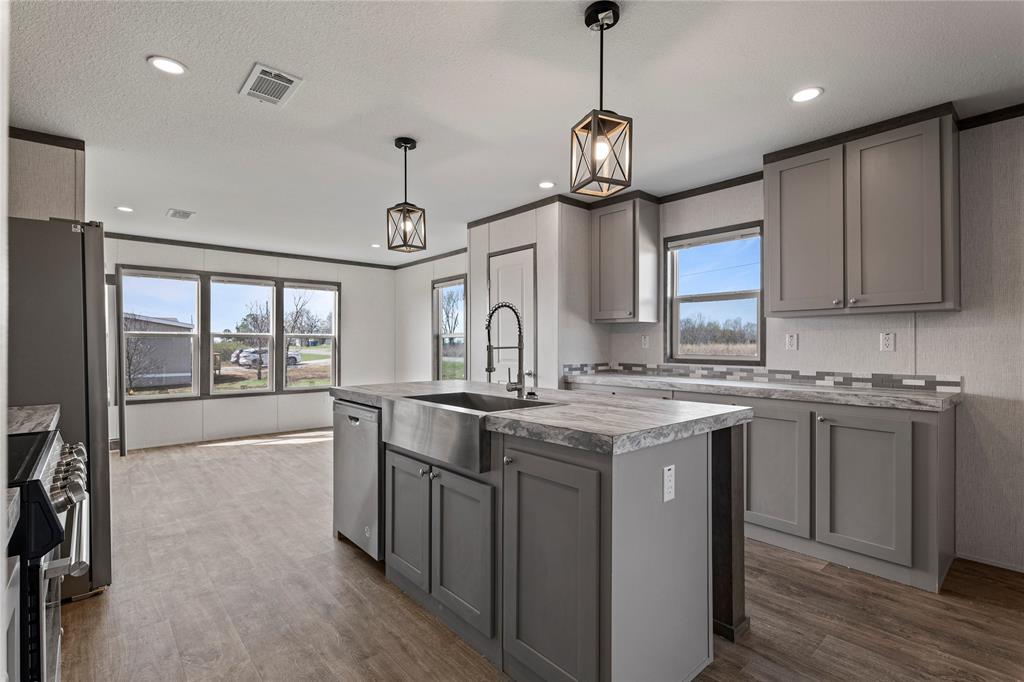 3888 Sandusky Road Whitesboro, TX 76273 - Photo 10 of 24 Kitchen featuring gray cabinets, dark wood-style floors, a kitchen island with sink, hanging light fixtures, and stainless steel appliances