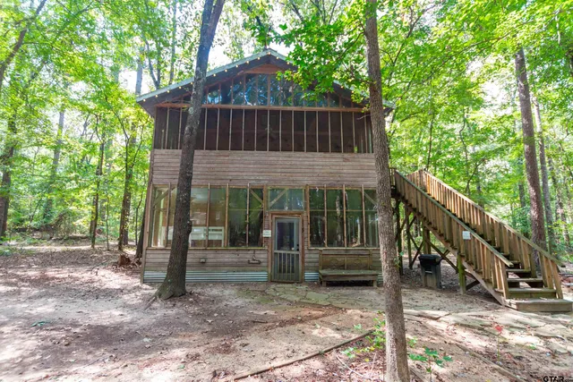 a view of small wooden house with a small yard and large trees