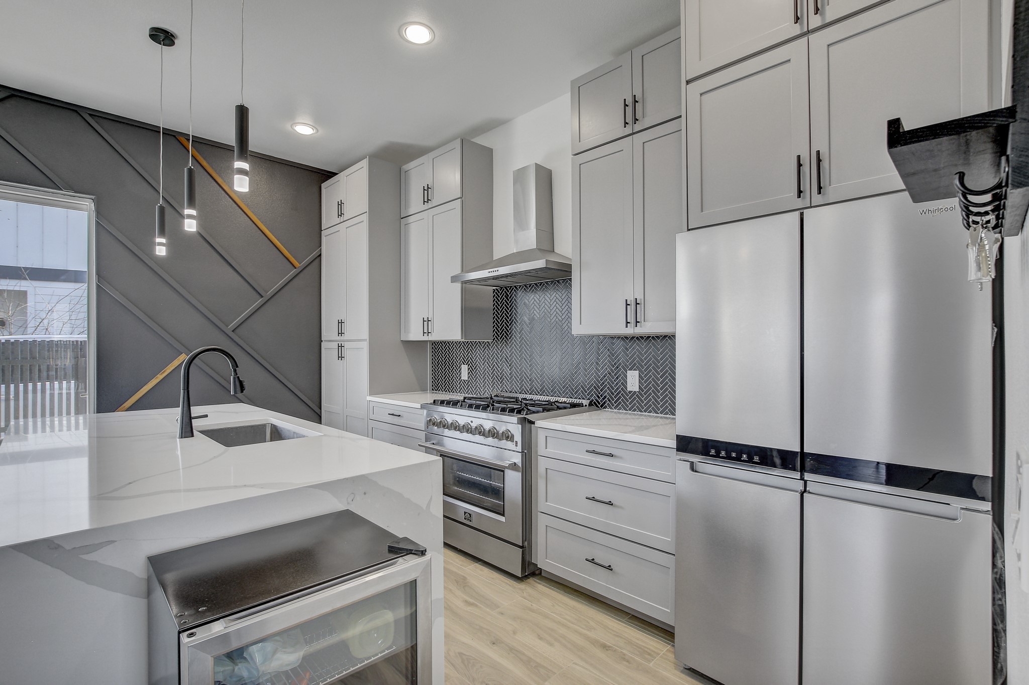 4703 Louis Avenue, Unit A Austin, TX 78721 - Photo 12 of 35 Kitchen with stainless steel appliances, light stone countertops, pendant lighting, light wood-style floors, and backsplash