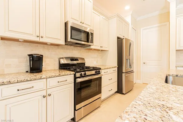 a kitchen with stainless steel appliances kitchen island granite countertop a table chairs and a refrigerator