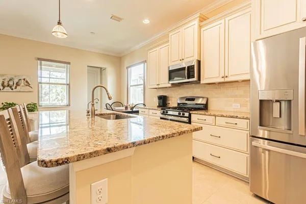 a kitchen with kitchen island a dining table chairs stainless steel appliances and cabinets