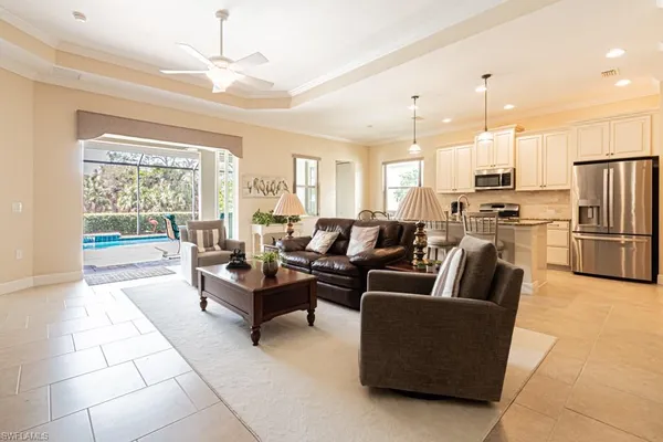 a living room with couches and kitchen view with wooden floor