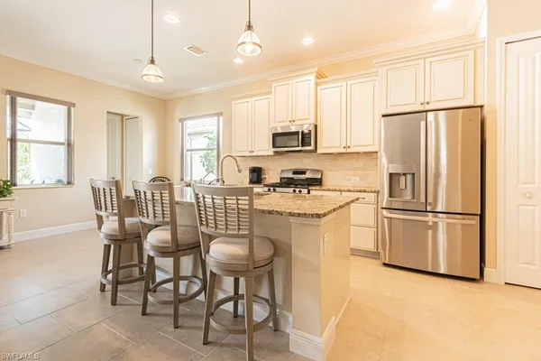 a kitchen with stainless steel appliances a refrigerator a stove a dining table and chairs with wooden floor