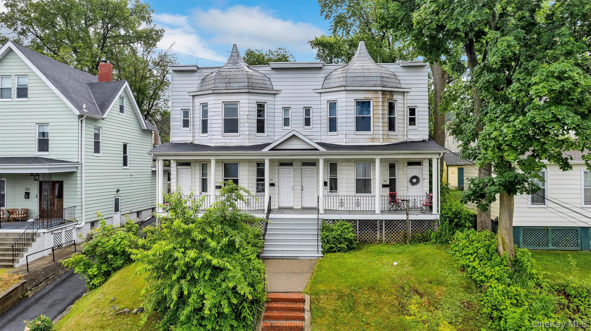 Victorian house with a porch, stairway, and a front yard