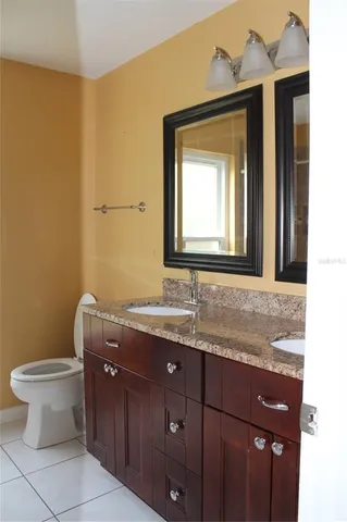a bathroom with a granite countertop sink toilet and mirror