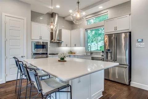 a kitchen with stainless steel appliances granite countertop a kitchen island a stove a table and chairs