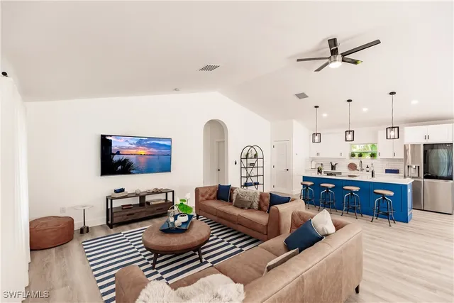 a kitchen with stainless steel appliances kitchen island a table chairs and a refrigerator