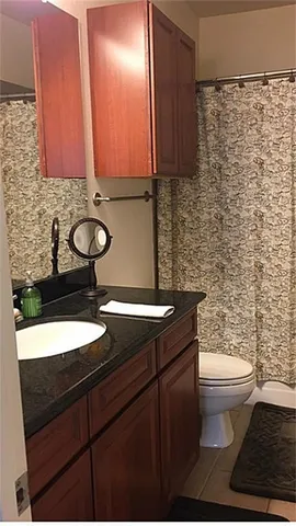 a bathroom with a granite countertop sink a toilet and a mirror
