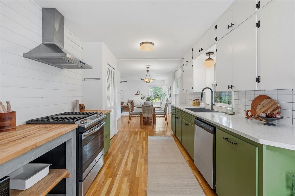 900 Stark Street Austin, TX 78756 - Photo 10 of 25 A well-appointed kitchen features vibrant green cabinetry, stainless steel appliances, and gleaming hardwood flooring.