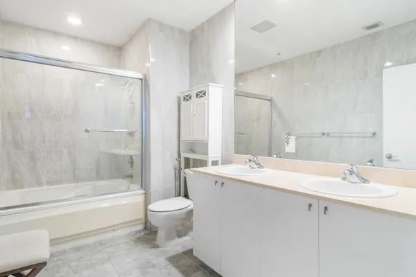a bathroom with a double vanity sink toilet mirror and bathtub