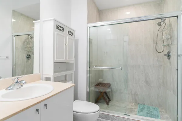 a bathroom with a shower sink vanity mirror and toilet