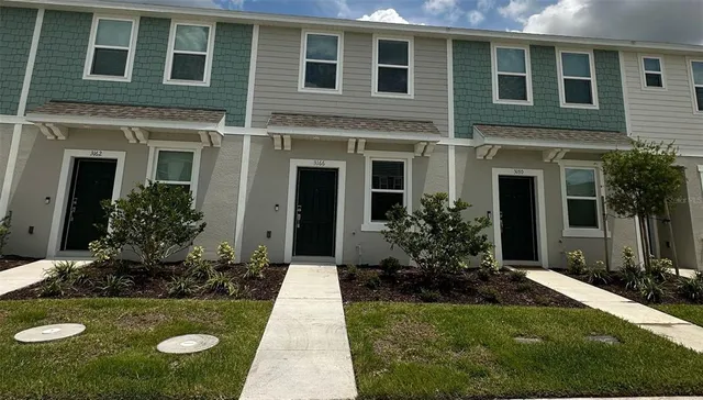 a view of a house with potted plants and a yard in front of it