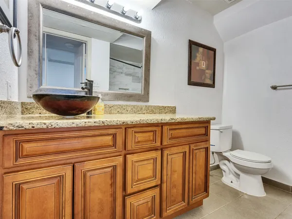 a bathroom with a granite countertop toilet sink and mirror