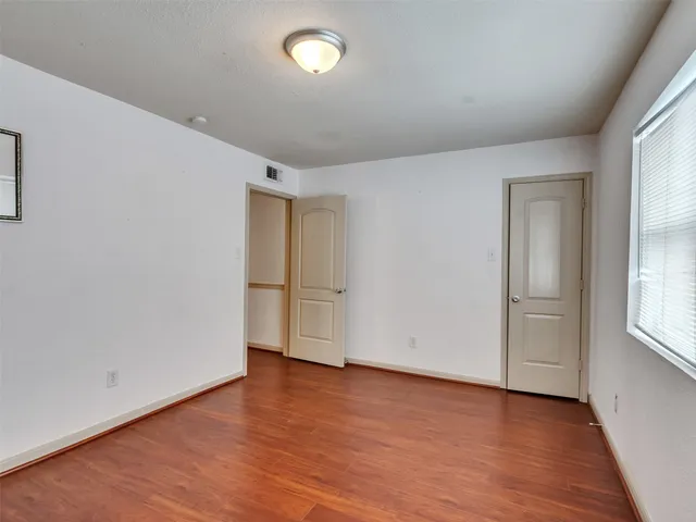 an empty room with wooden floor and windows