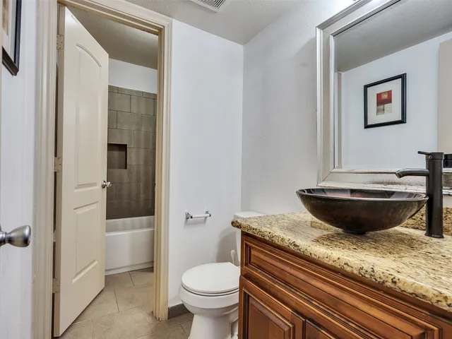 a bathroom with a granite countertop toilet and sink
