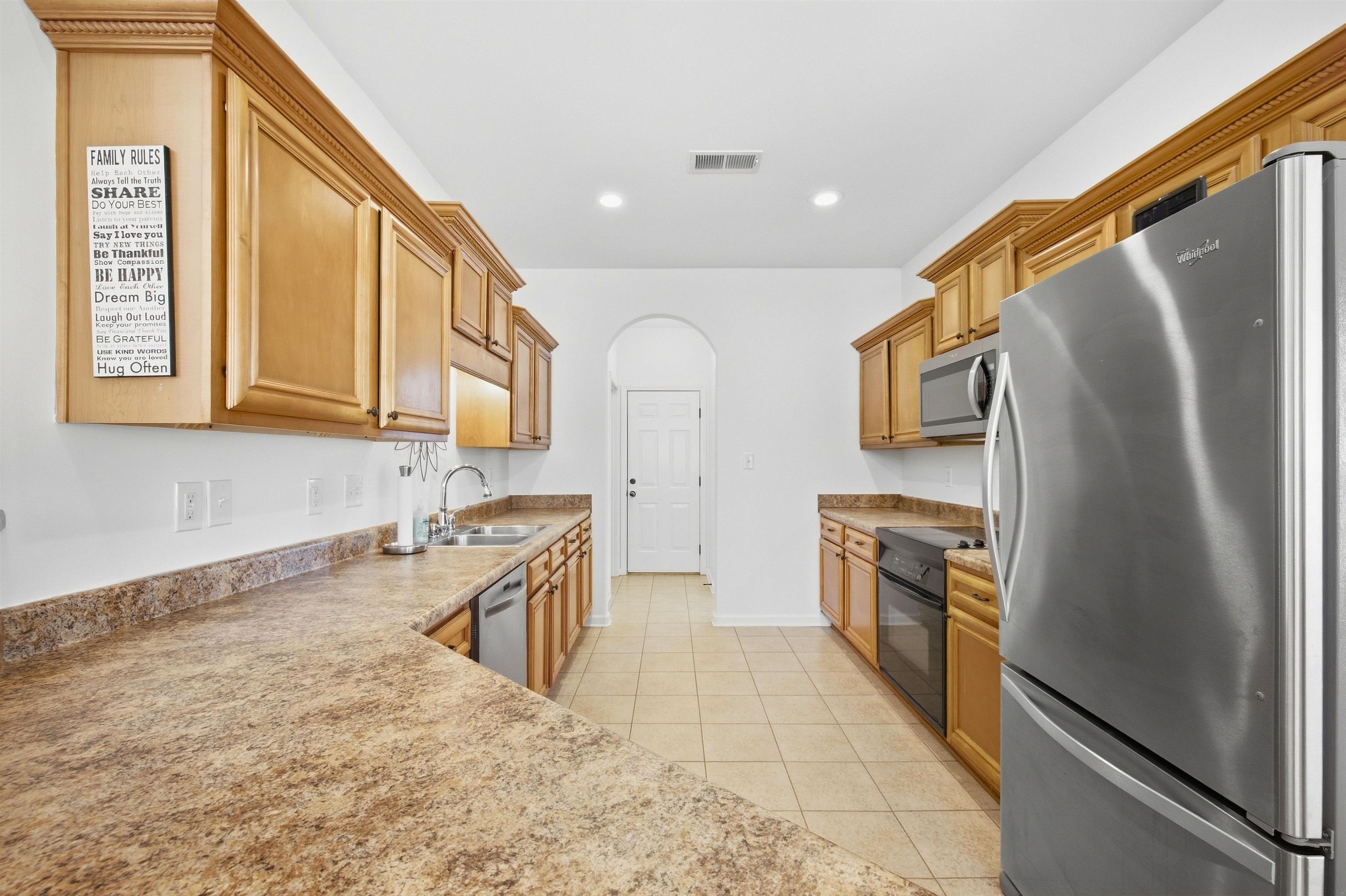 7920 Pips Ridge Lane Bartlett, TN 38133 - Photo 12 of 40 Warm-toned cabinetry, stainless steel appliances, a double basin sink, and tile flooring