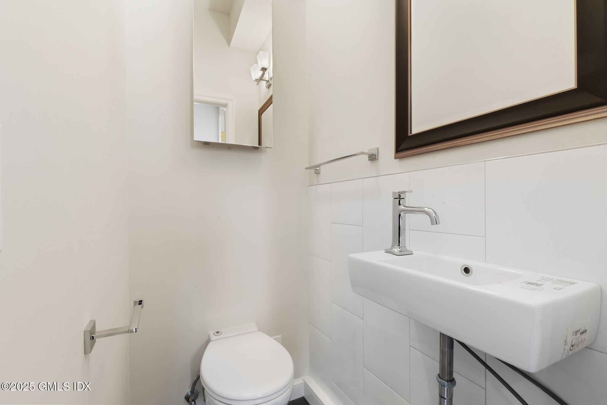 84 Indian Harbor Drive Greenwich, CT 06830 - Photo 14 of 16 a bathroom with a sink a toilet and mirror