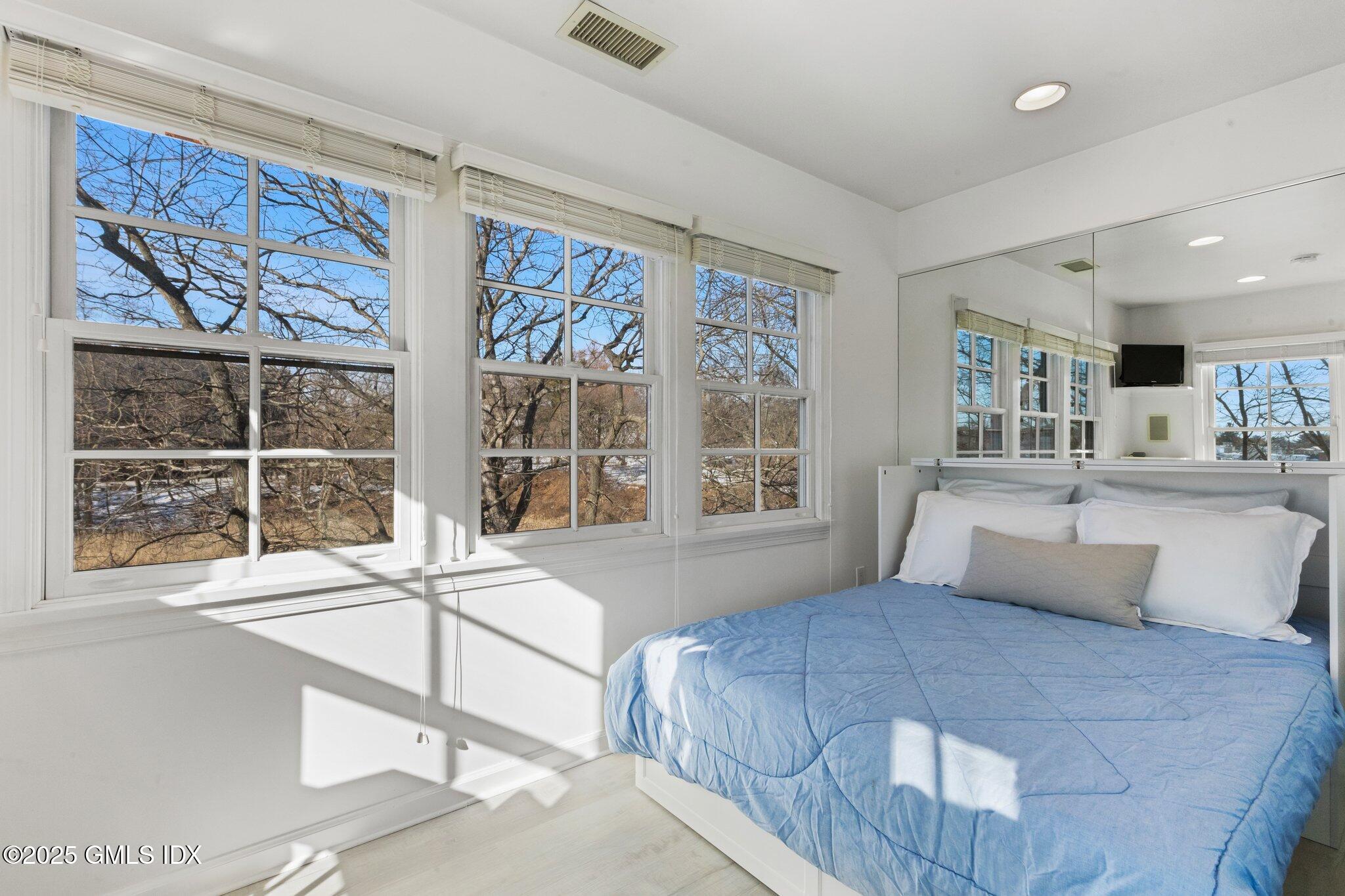 84 Indian Harbor Drive Greenwich, CT 06830 - Photo 10 of 16 a bedroom with a large bed and a large window