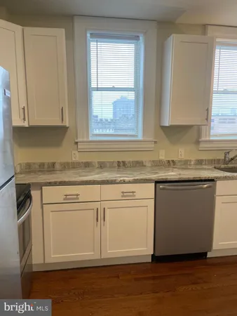 a kitchen with granite countertop white cabinets sink and window