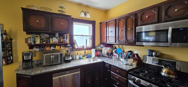 a kitchen with stainless steel appliances granite countertop a stove a sink and a microwave