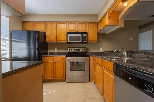 a kitchen with granite countertop a refrigerator and a stove top oven